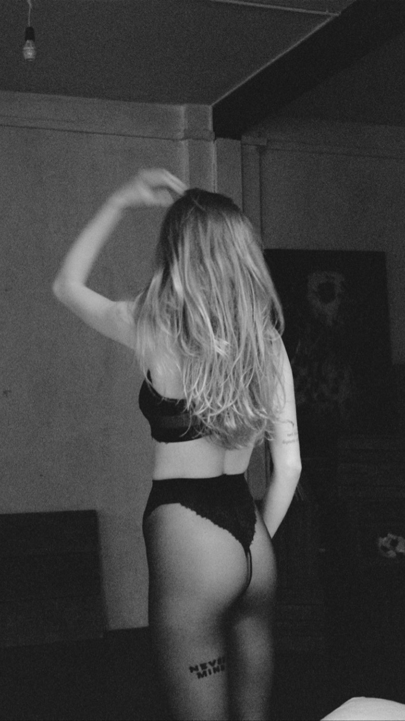 Black-and-white photograph of a model from behind in black lingerie and sheer tights